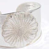 Silver bracelet with intricate floral design on a white background