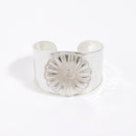 Silver cuff bracelet with a textured floral design on a white background