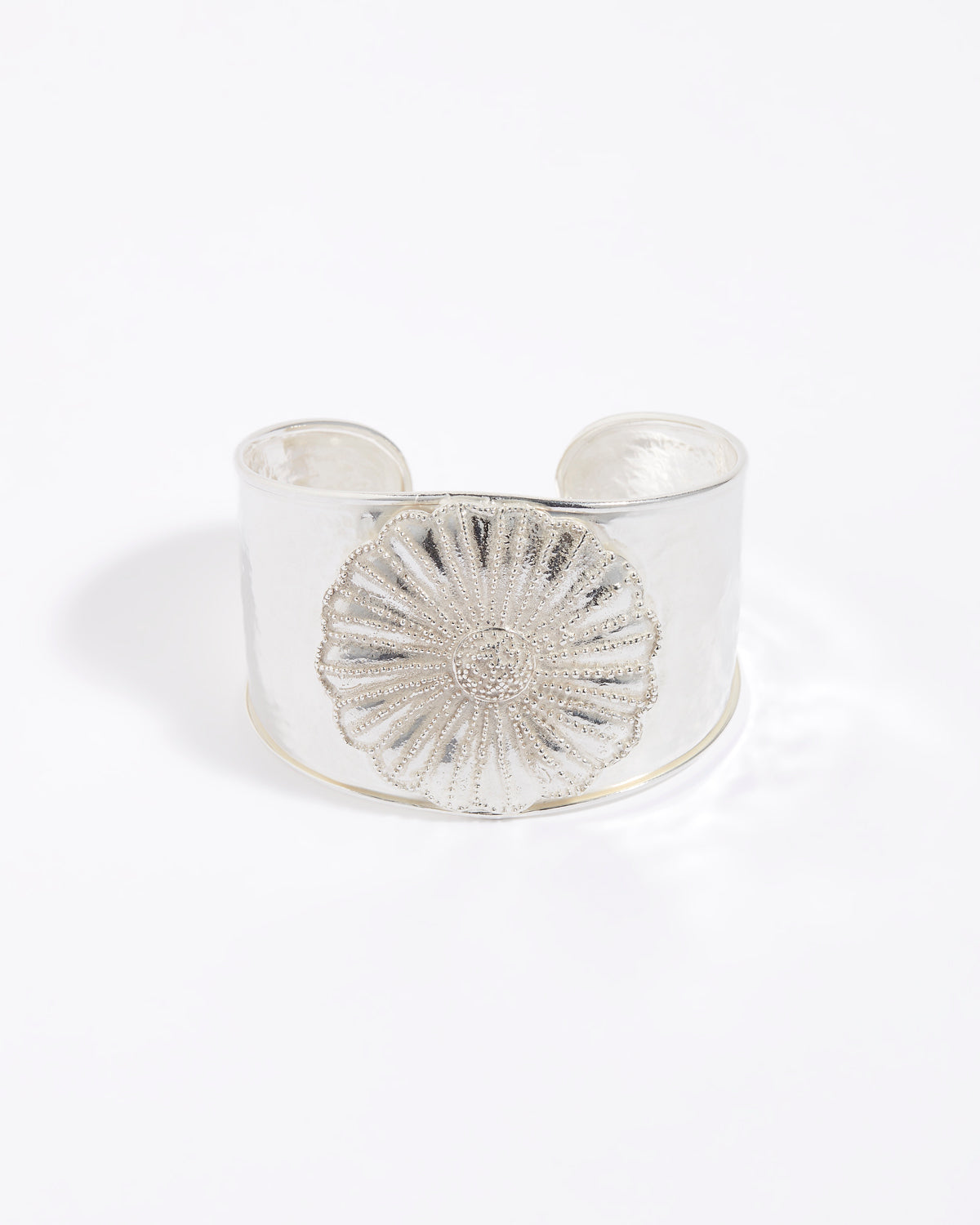 Silver cuff bracelet with a textured floral design on a white background