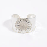 Silver cuff bracelet with a textured floral design on a white background