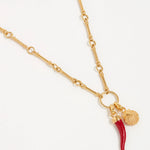 Image of a red coral Cornicello  horn shaped charm with gold top connector and a shell charm both hung from a gold bar necklace