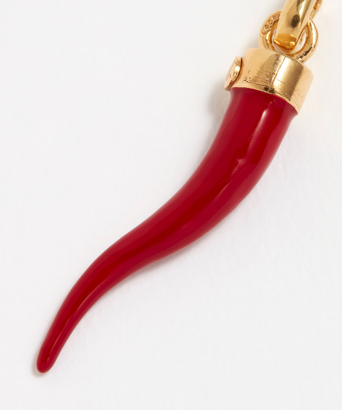 Close up Image of a red coral Cornicello horn shaped charm with gold top connector