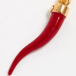 Close up Image of a red coral Cornicello horn shaped charm with gold top connector