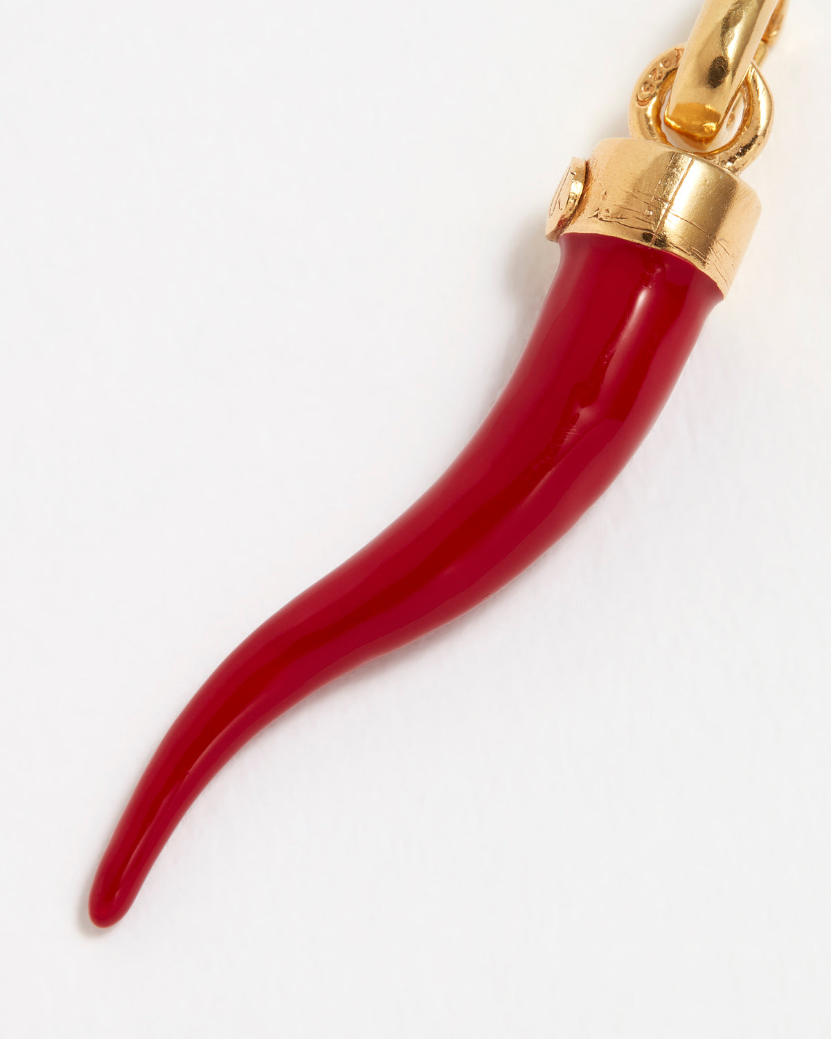 Close up Image of a red coral Cornicello horn shaped charm with gold top connector