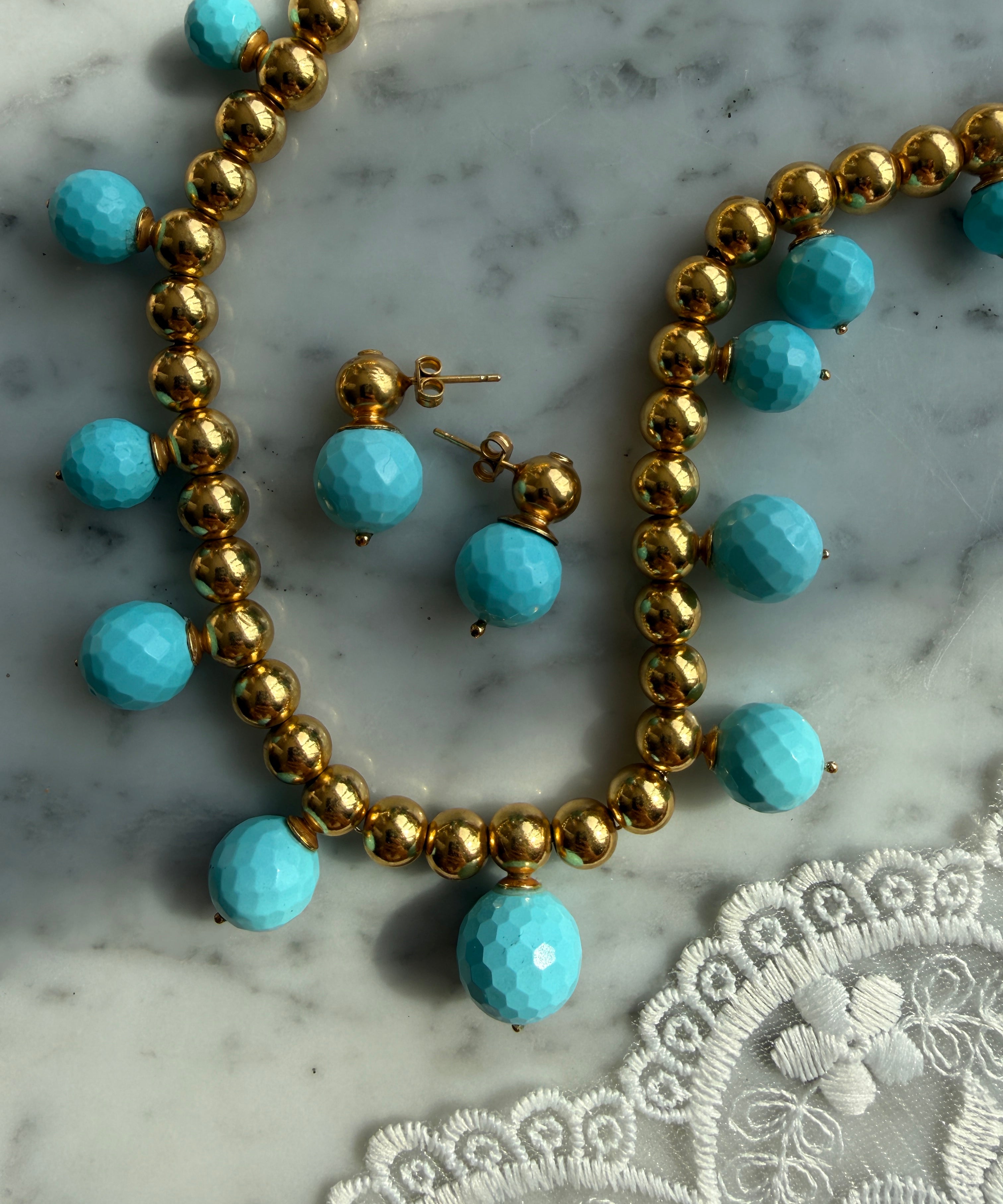 turquoise beaded necklace and earrings laid on marble 