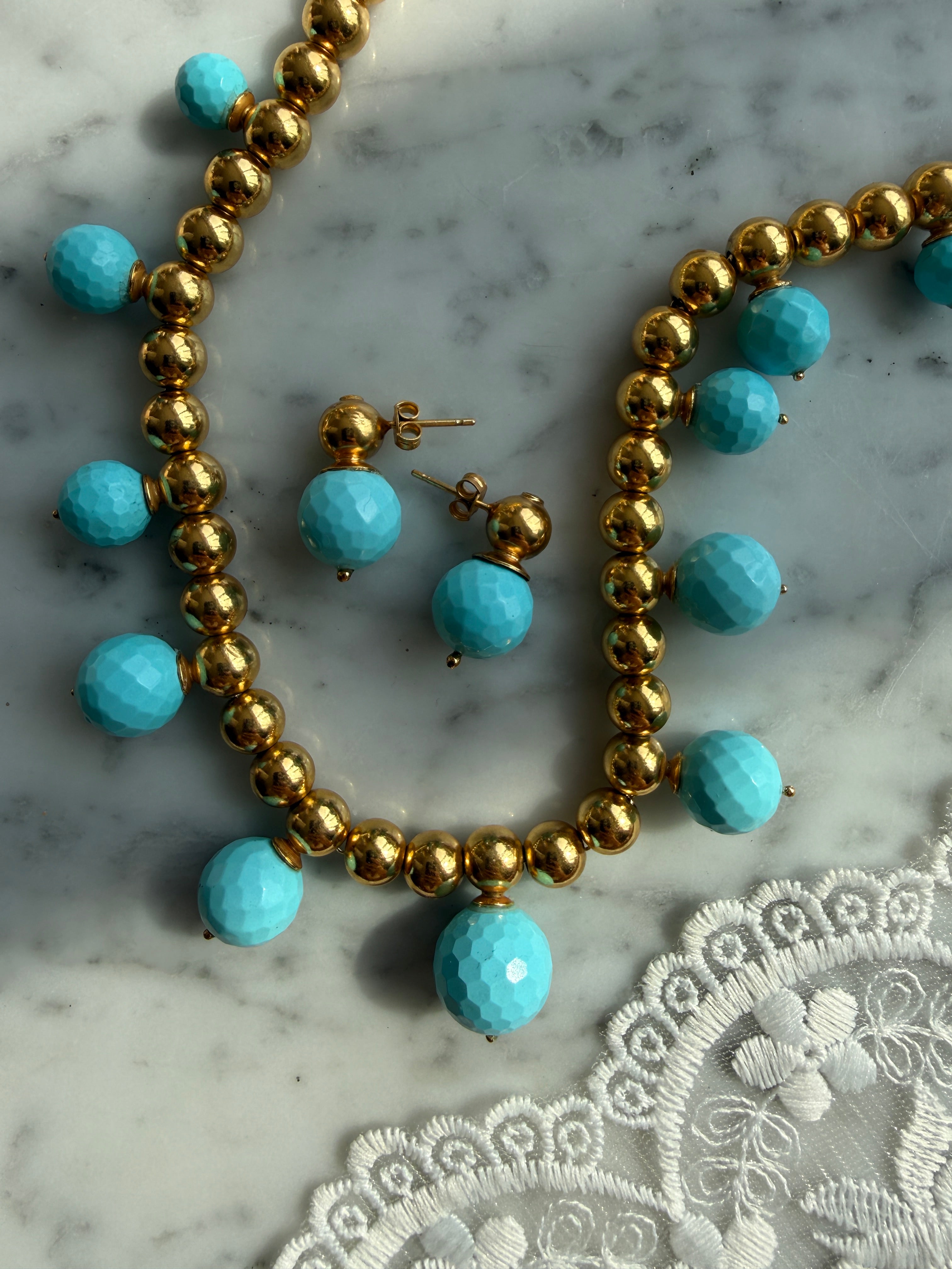 turquoise beaded necklace and earrings laid on marble 