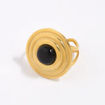 Gold ring with a round domed onyx gemstone set within circular gold frame,on a white background