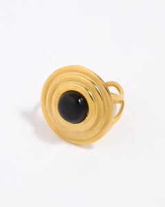 Gold ring with a round domed onyx gemstone set within circular gold frame,on a white background