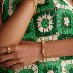 Close up model shot wearing bracelet with textured bar and pearls and also a chunky gold bracelet with a gold ring