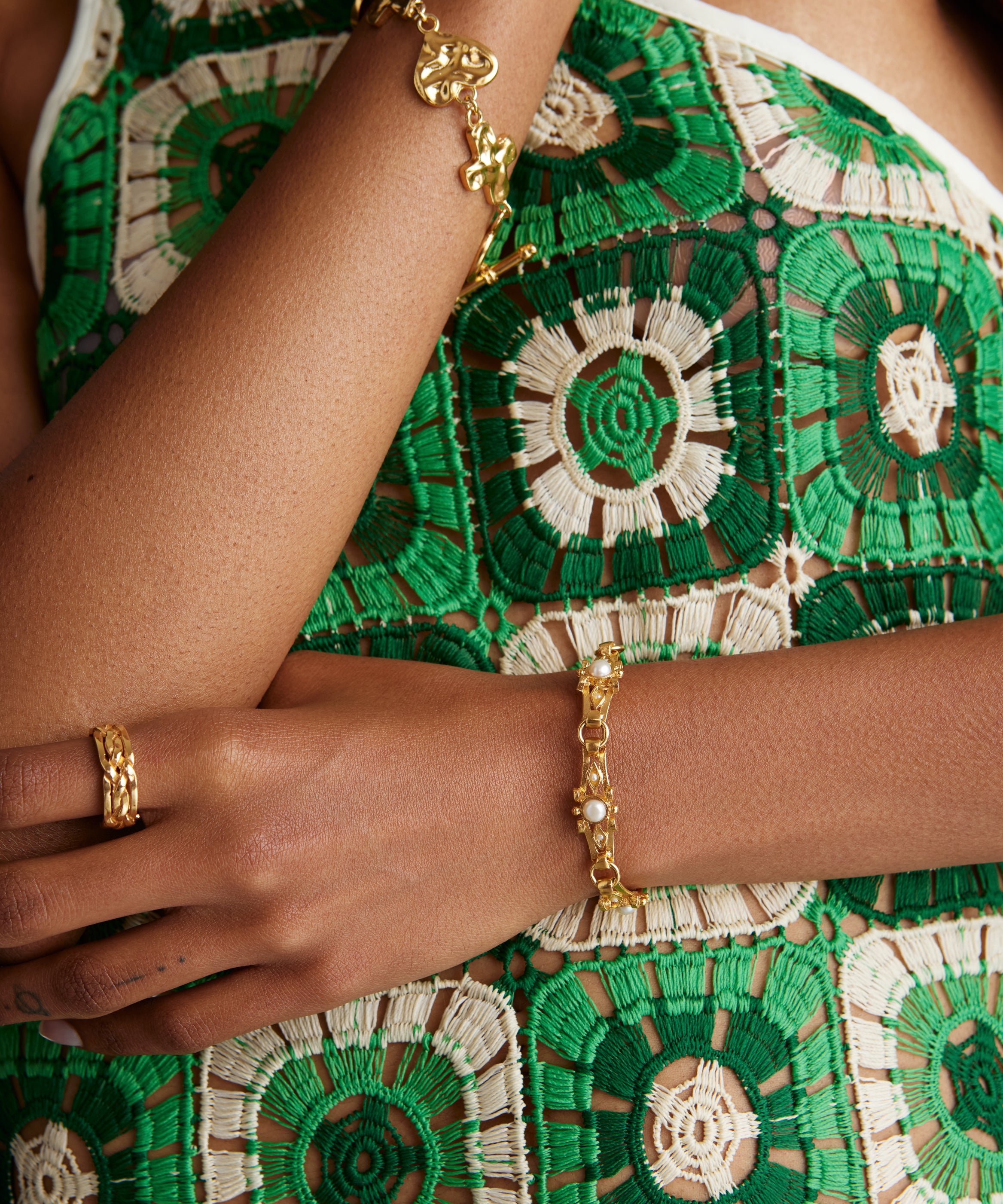 Close up model shot wearing bracelet with textured bar and pearls and also a chunky gold bracelet with a gold ring