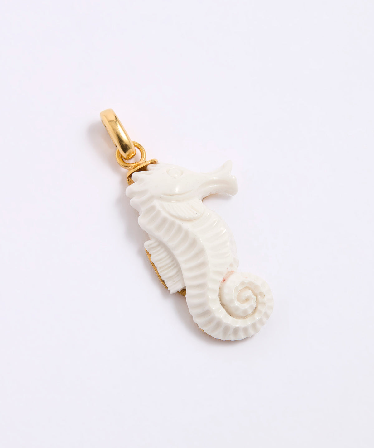 White seahorse pendant with gold clasp  on a grey background