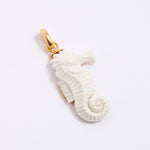 White seahorse pendant with gold clasp  on a grey background