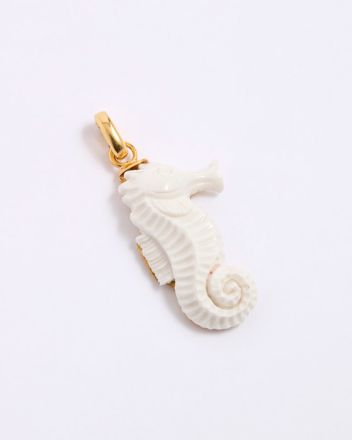 White seahorse pendant with gold clasp  on a grey background