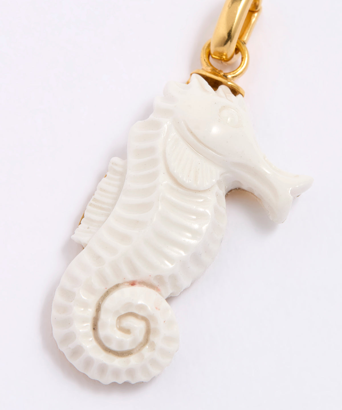 White seahorse pendant with gold clasp on a white background