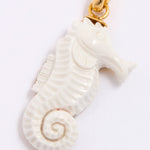 White seahorse pendant with gold clasp on a white background