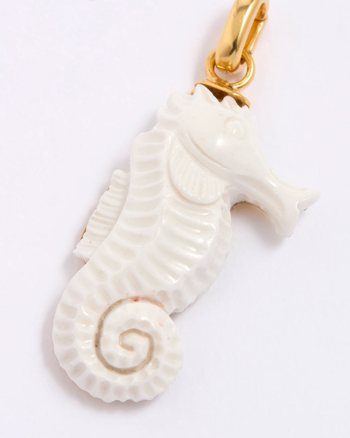 White seahorse pendant with gold clasp on a white background