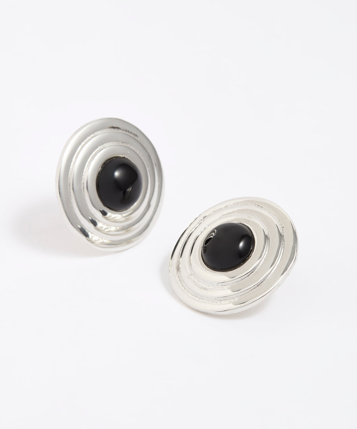 Pair of silver round earrings with black onyx stones in the centre, on a white background