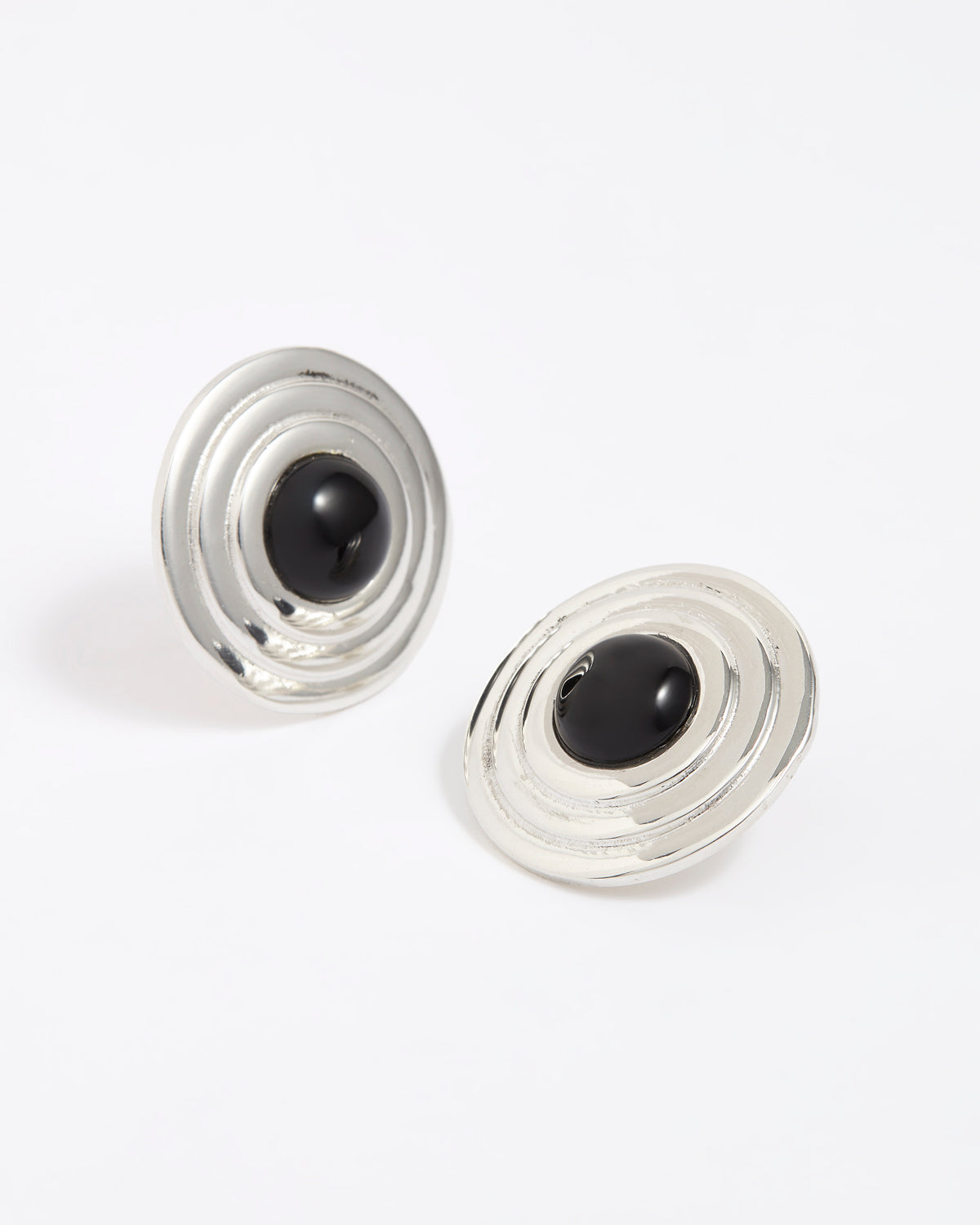 Pair of silver round earrings with black onyx stones in the centre, on a white background