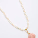 Pearl necklace with a pink shell pendant on a white background