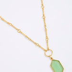 Gold coloured necklace with a green pendant on a white background