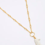 Gold necklace with a white seahorse pendant on a light gray background