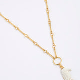 Gold necklace with a white seahorse pendant on a light gray background