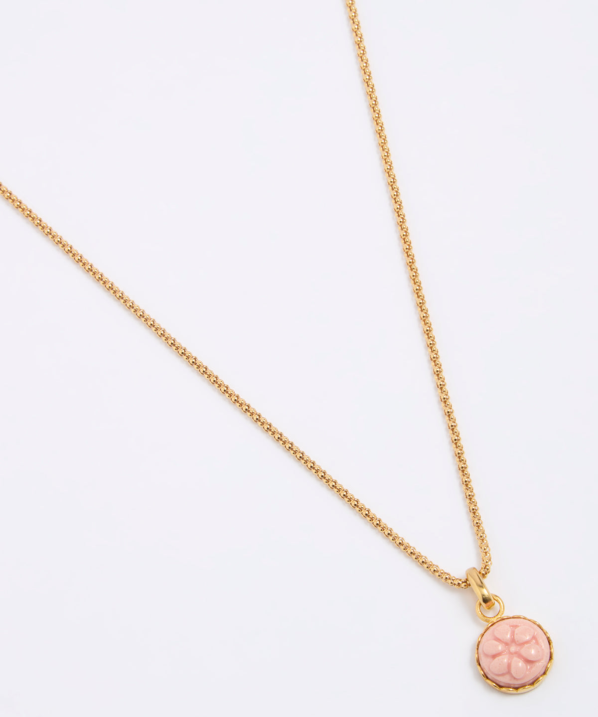 Gold coloured necklace with a pink pendant on a white background