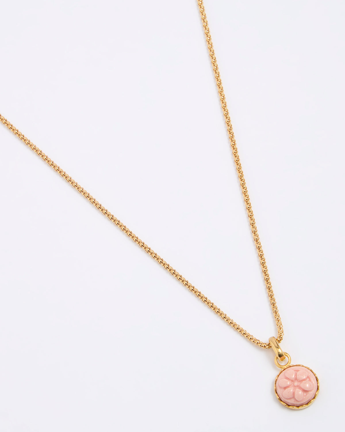 Gold coloured necklace with a pink pendant on a white background