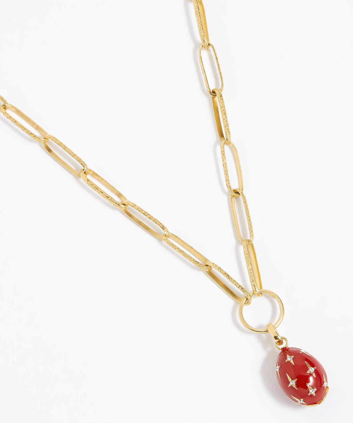 Red egg-shaped pendant with gold accents and crystal star designs attached to a gold charm chain,  on a white background