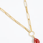Red egg-shaped pendant with gold accents and crystal star designs attached to a gold charm chain,  on a white background