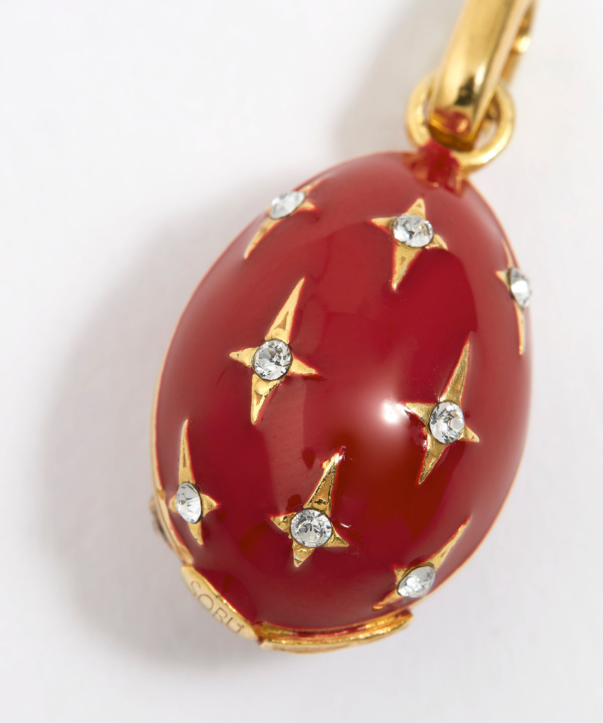 Red egg-shaped pendant with gold accents and crystal star designs on a white background