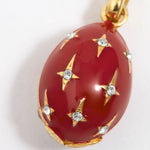 Red egg-shaped pendant with gold accents and crystal star designs on a white background