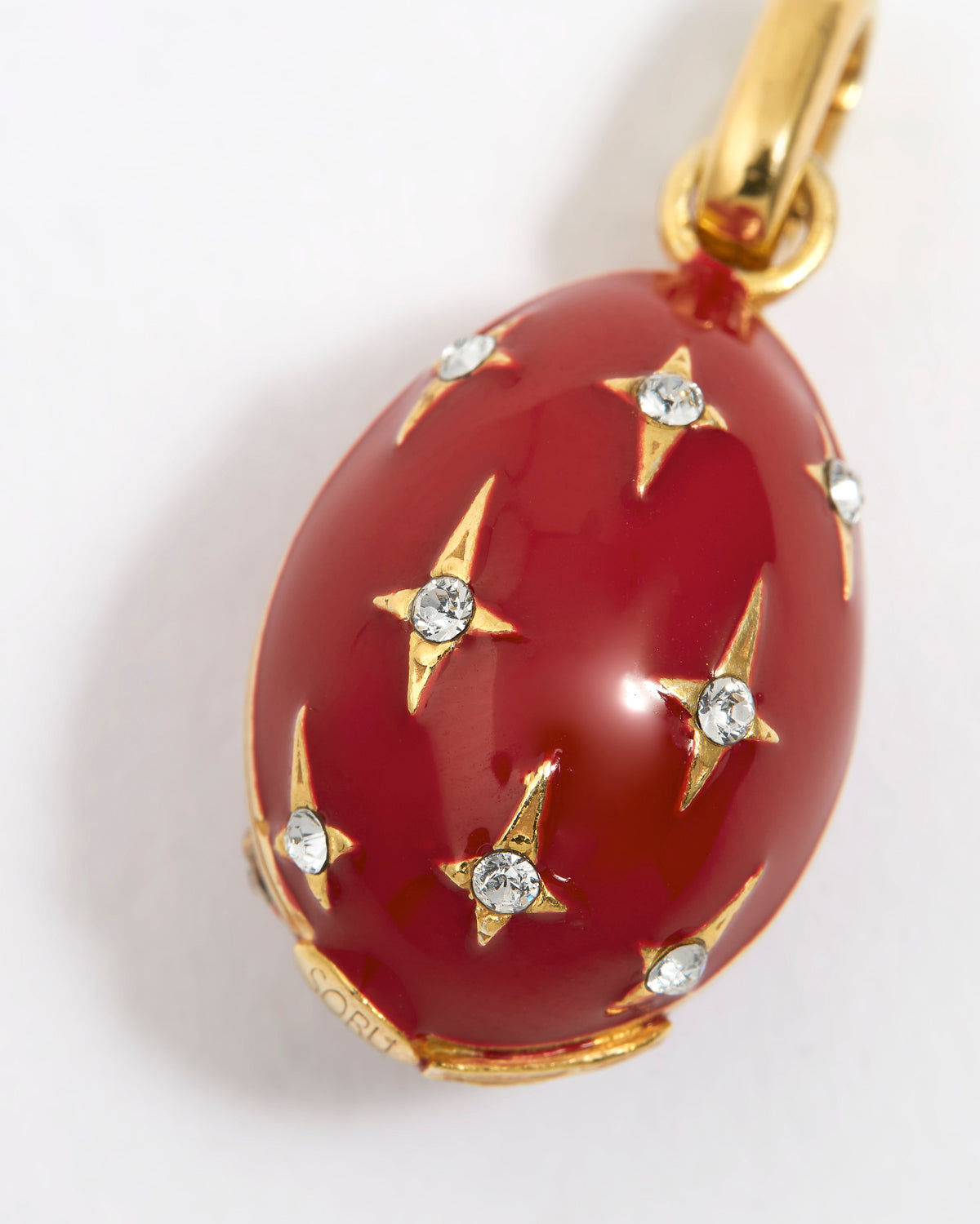 Red egg-shaped pendant with gold accents and crystal star designs on a white background