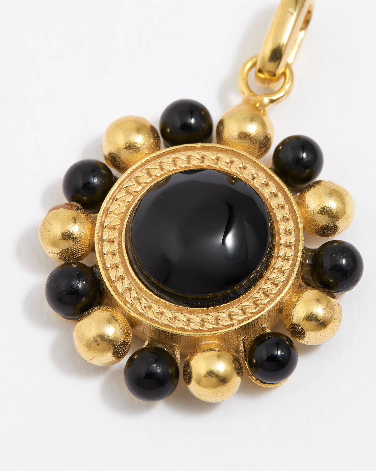 close up image of Gold circular charm pendant with central onyx stone with black and gold beaded edge,  on a white background