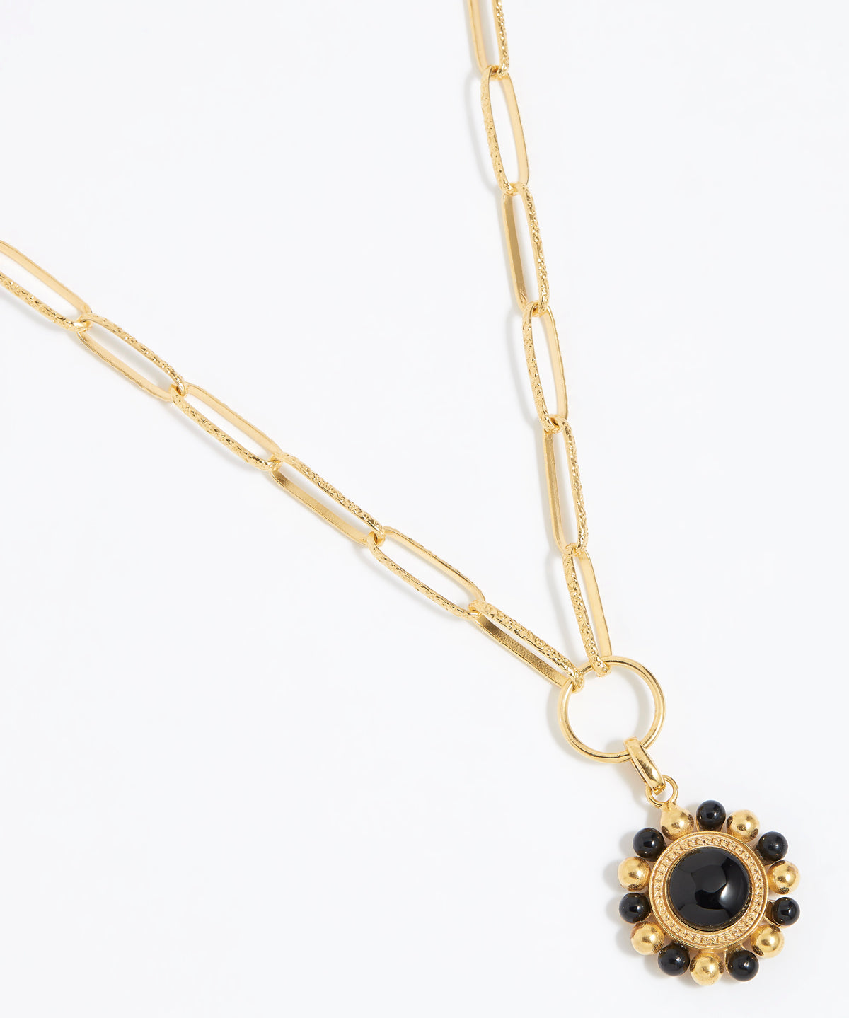 Gold circular charm pendant with central onyx stone with black and gold beaded edge hanging on a charm chain,  on a white background