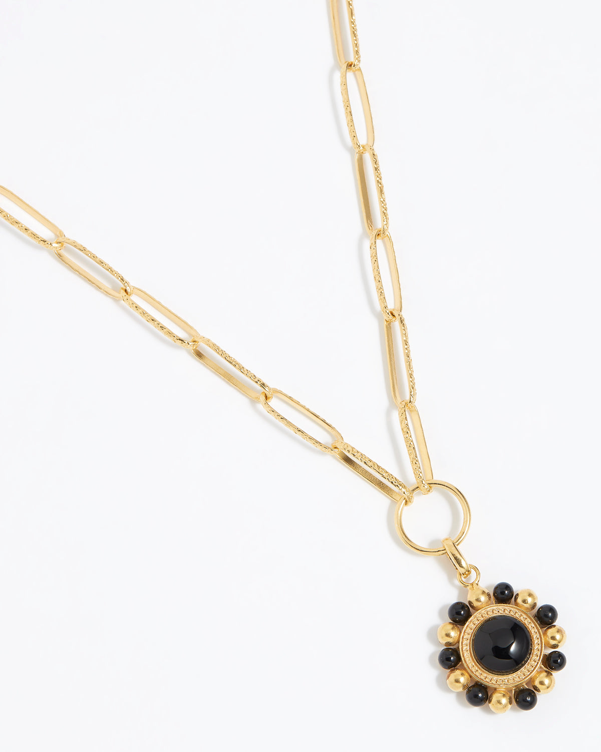 Gold circular charm pendant with central onyx stone with black and gold beaded edge hanging on a charm chain,  on a white background