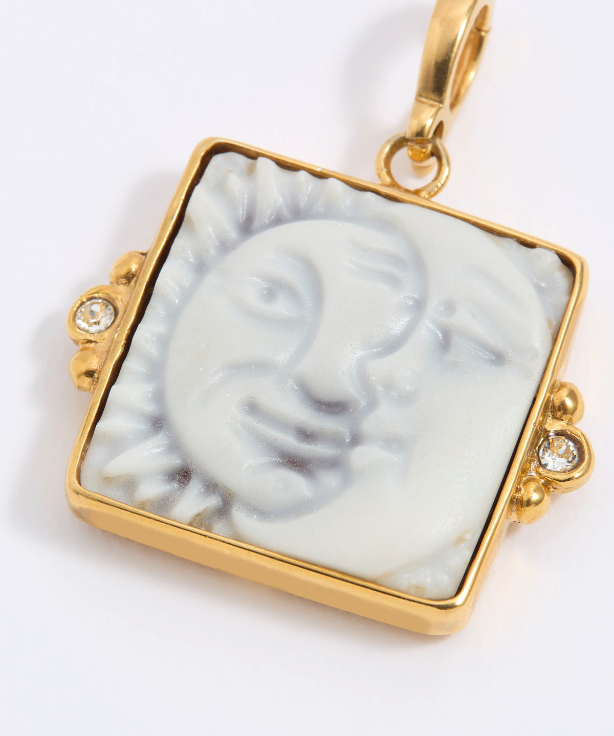 Gold-framed square pendant with a face of a sun and moon design set on a square tile on a white background