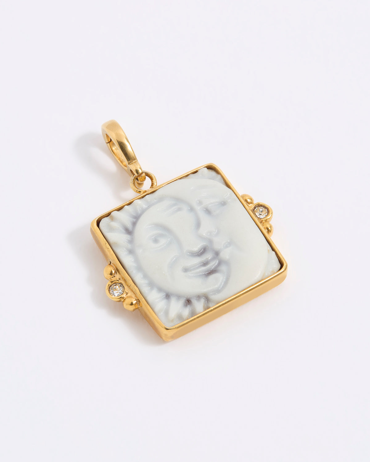 Gold-framed square pendant with a face of a sun and moon design set on a square tile on a white background