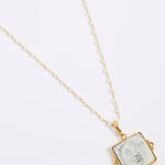 Gold-framed square pendant with a face of a sun and moon design set on a square tile hung from a peal chain on a white background