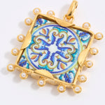 Decorative pendant with blue and gold design on a square tile with mini pearl edging  on a white background