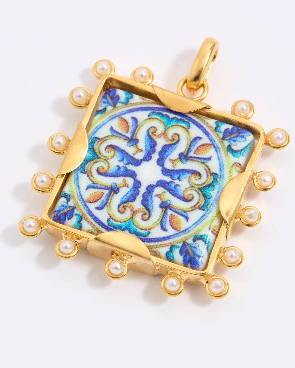 Decorative pendant with blue and gold design on a square tile with mini pearl edging  on a white background