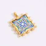 Decorative pendant with blue and gold design on a square tile with mini pearl edging  on a white background
