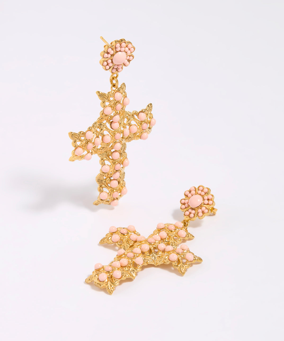Gold and pink cross-shaped earrings on a white background
