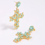 Gold cross-shaped earrings with turquoise stones on a white background