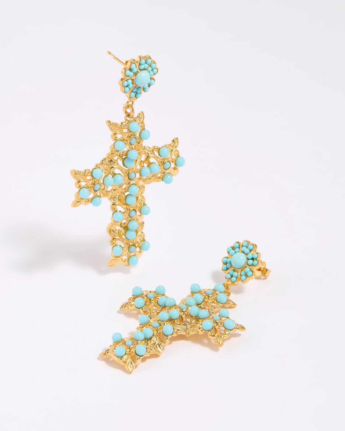 Gold cross-shaped earrings with turquoise stones on a white background