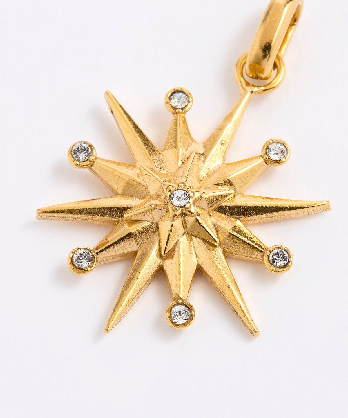 A gold 12-pointed starburst pendant charm with a central star and small clear gemstones at each point, shown on a plain white background.