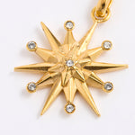 A gold 12-pointed starburst pendant charm with a central star and small clear gemstones at each point, shown on a plain white background.