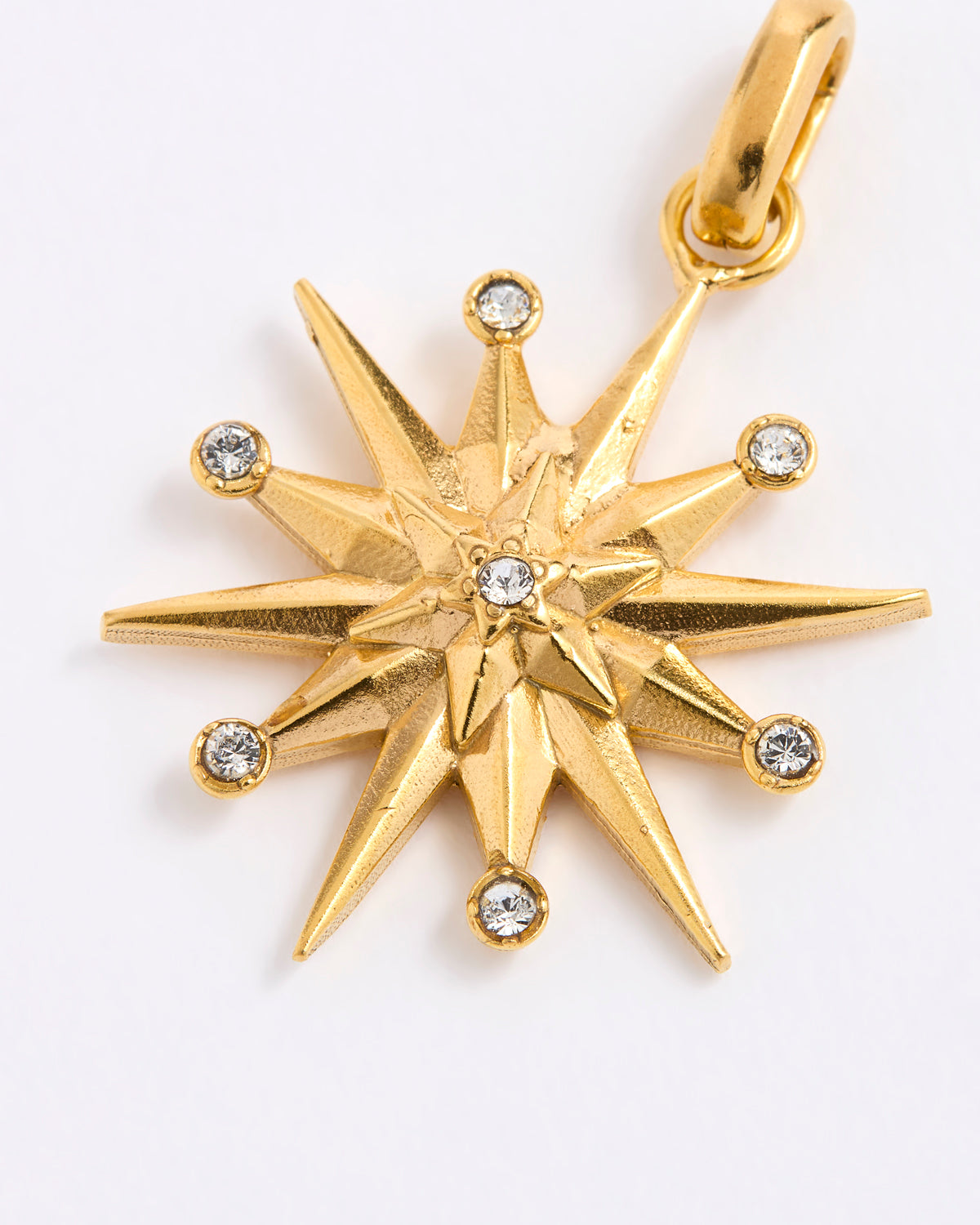 A gold 12-pointed starburst pendant charm with a central star and small clear gemstones at each point, shown on a plain white background.