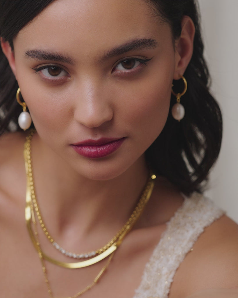 Soru Jewellery video of model wearing small gold hoop earrings with single pearl handing, made form gold plated silver